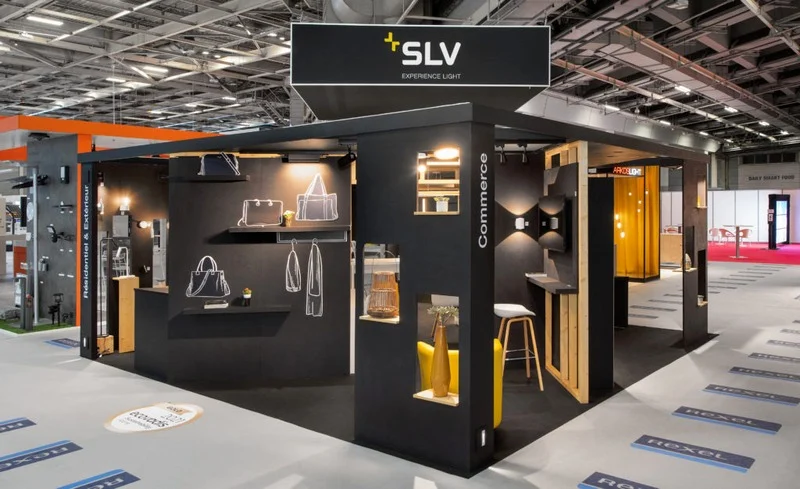 Stand d'exposition moderne SLV, mettant en avant des éclairages et des accessoires de design dans un cadre industriel avec des matériaux élégants et un agencement fonctionnel